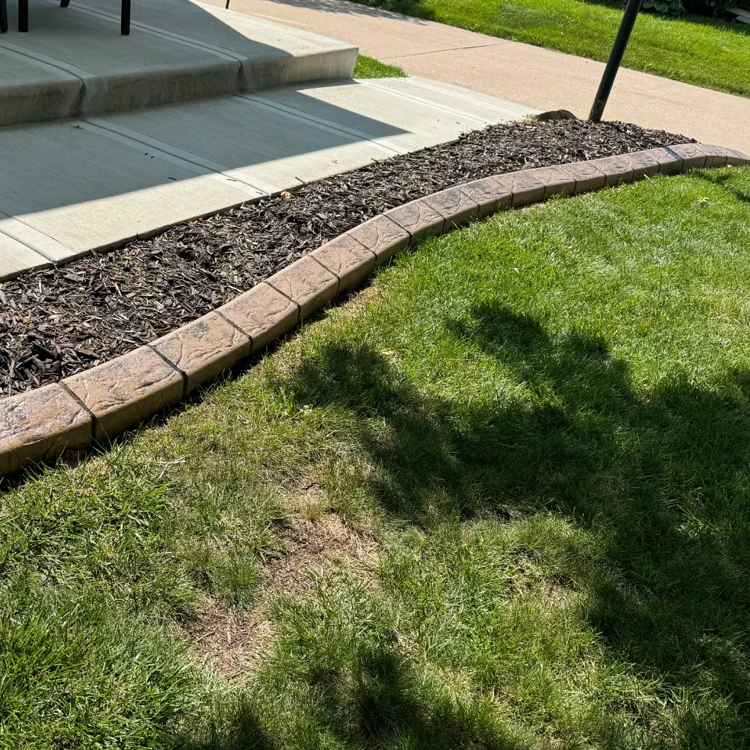 Stamped decorative concrete curbing with brick pattern along a landscaped residential yard